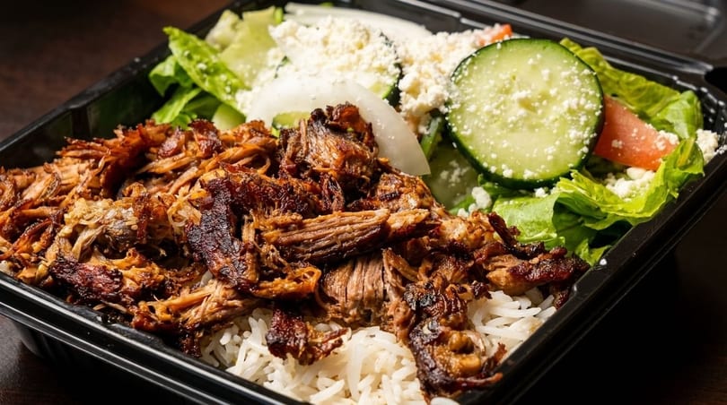 Shredded meat and rice with a side salad of lettuce, cucumber, tomato, and feta cheese.